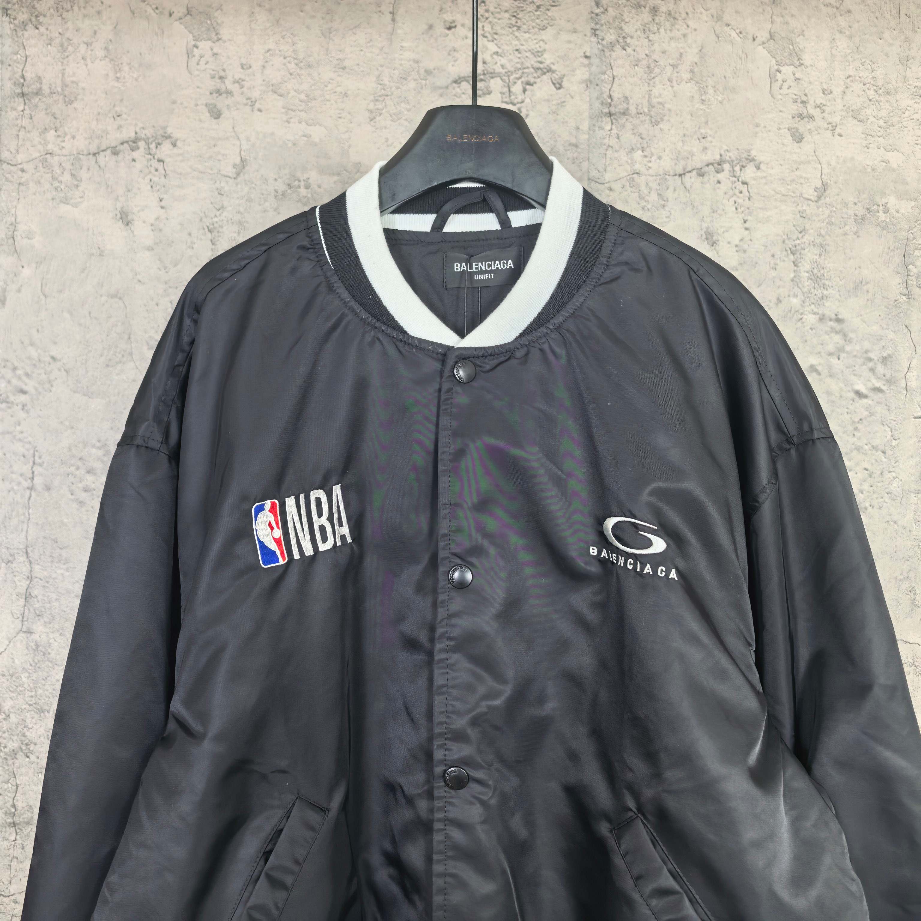 Black varsity bomber jacket with white-trim V-neck collar and NBA patch
