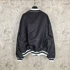 Black varsity bomber jacket, back view, with white striped ribbed hem
