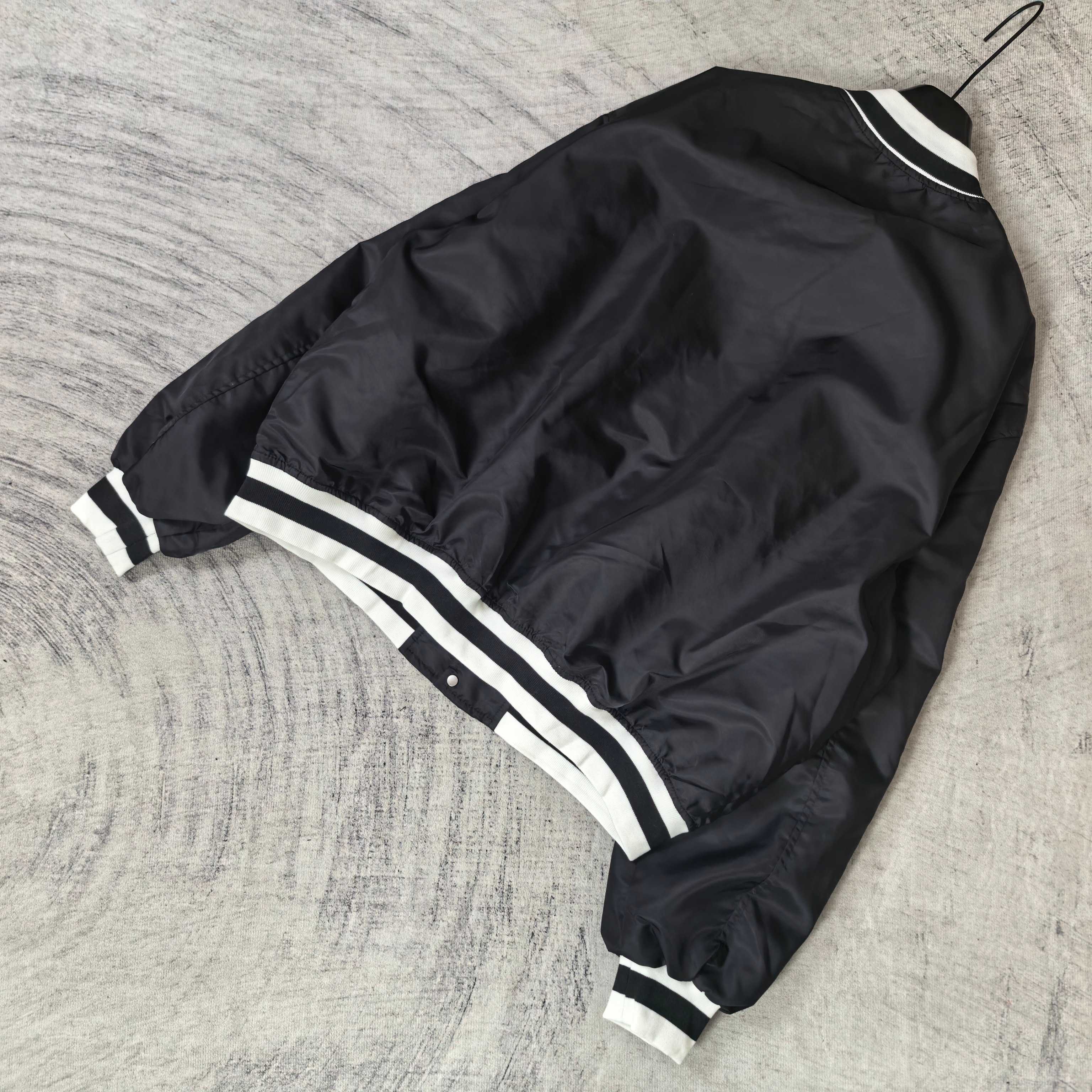 Black varsity bomber jacket with white stripe detailing at hem and cuffs