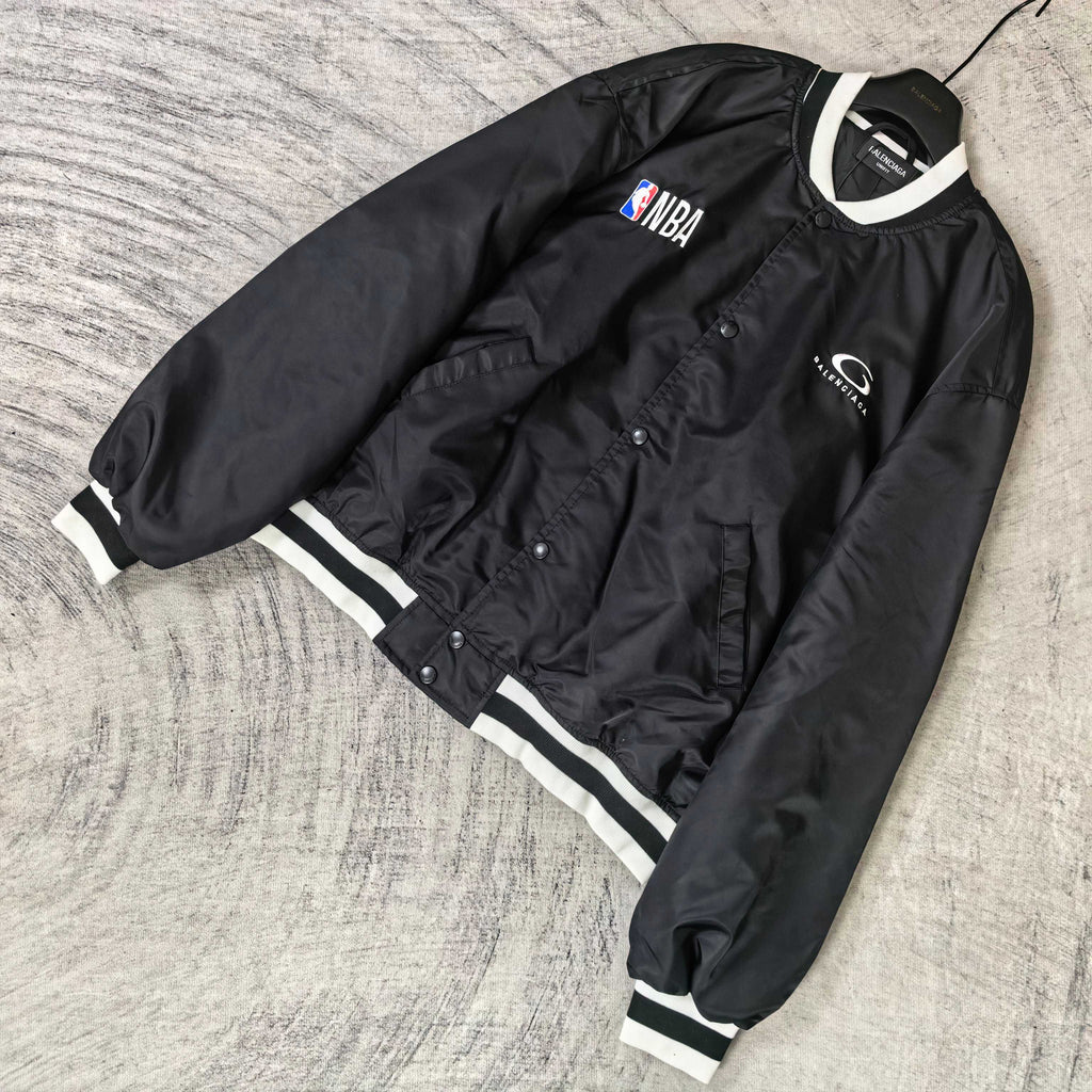 Black bomber jacket with NBA patch, snap front, and white striped cuffs