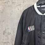 Black bomber jacket with NBA patch on chest and white-trim V-neck collar