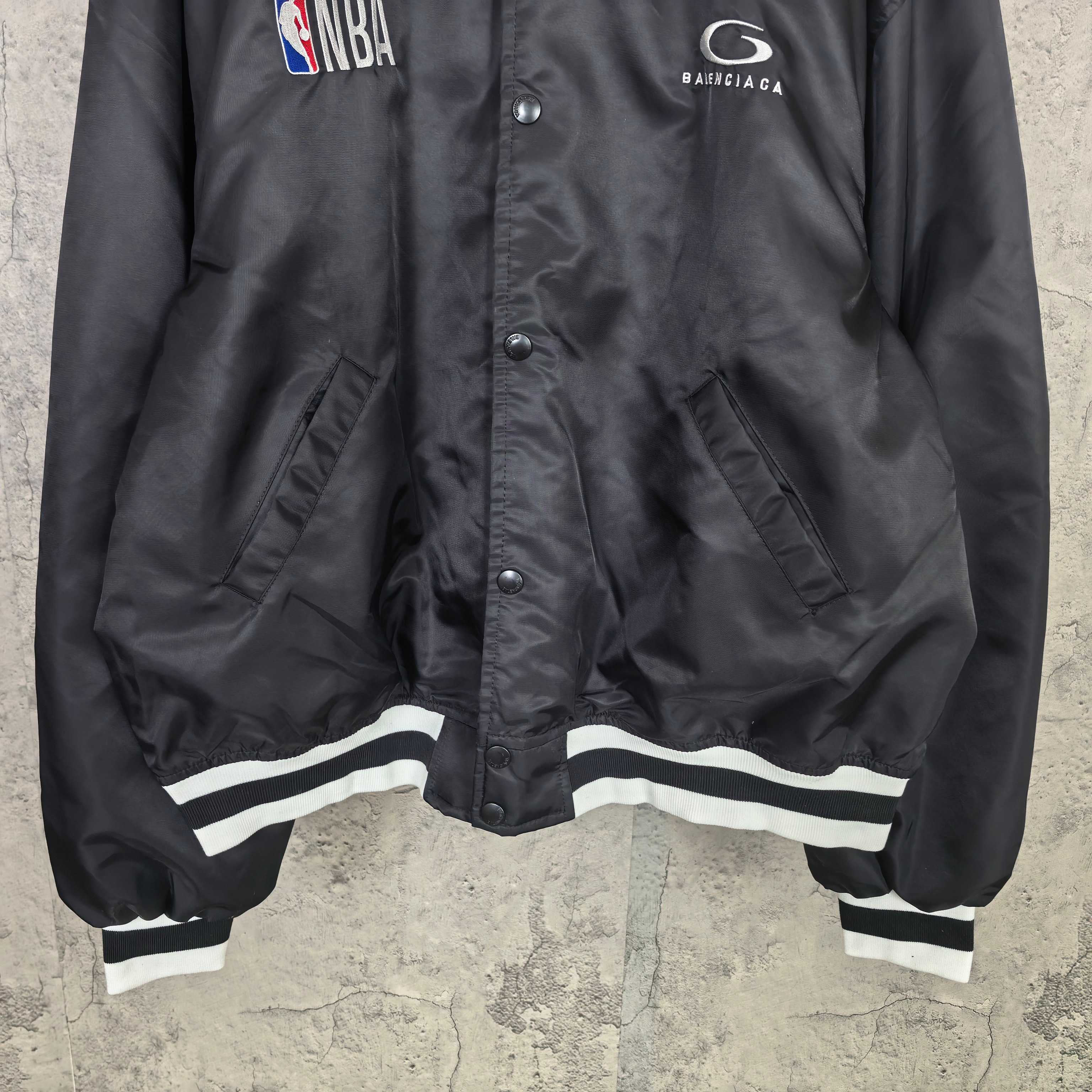 Black bomber jacket front with snap placket and white striped hem trim