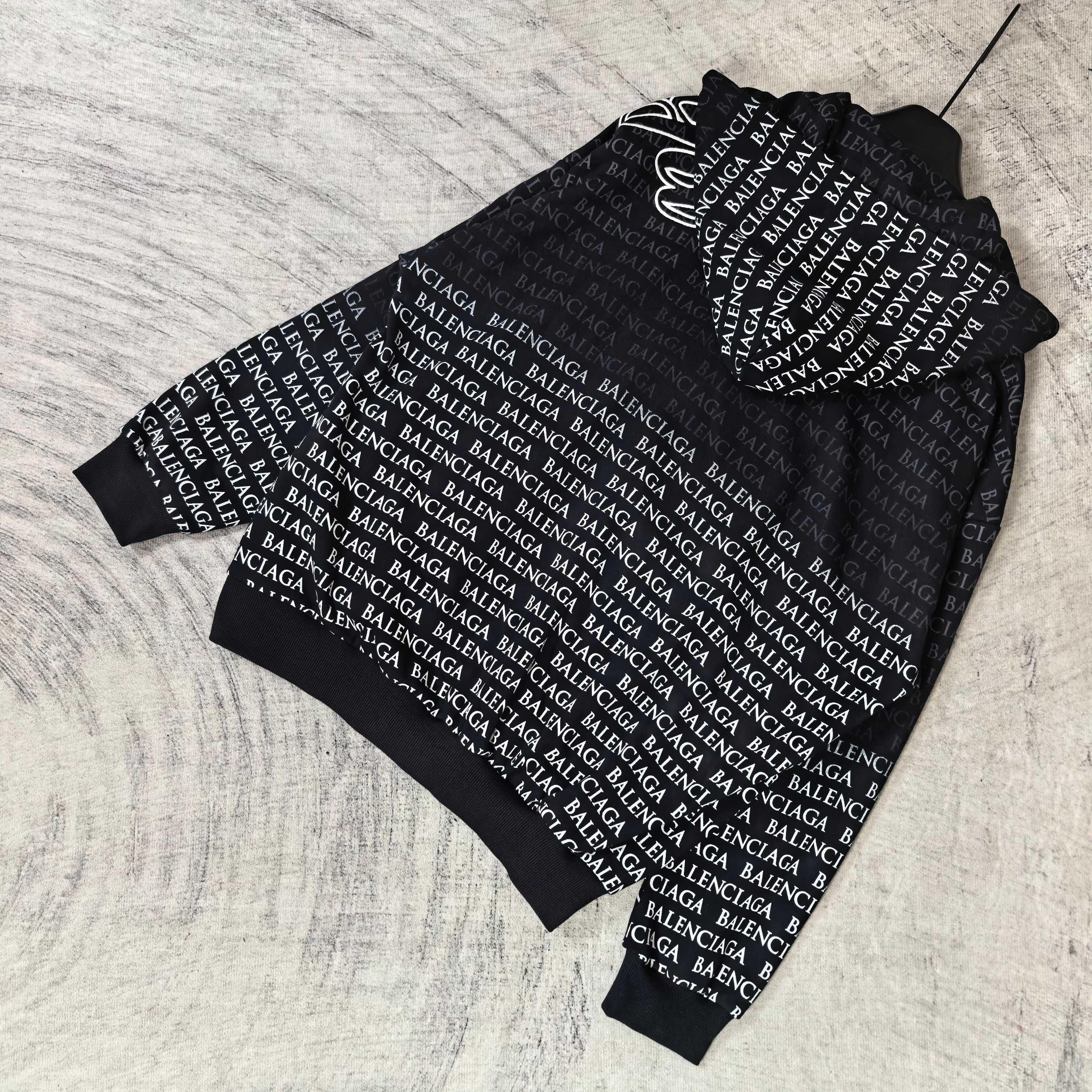 Balenciaga zip-up hoodie, black with hood and zipper; repeating text pattern and white logo