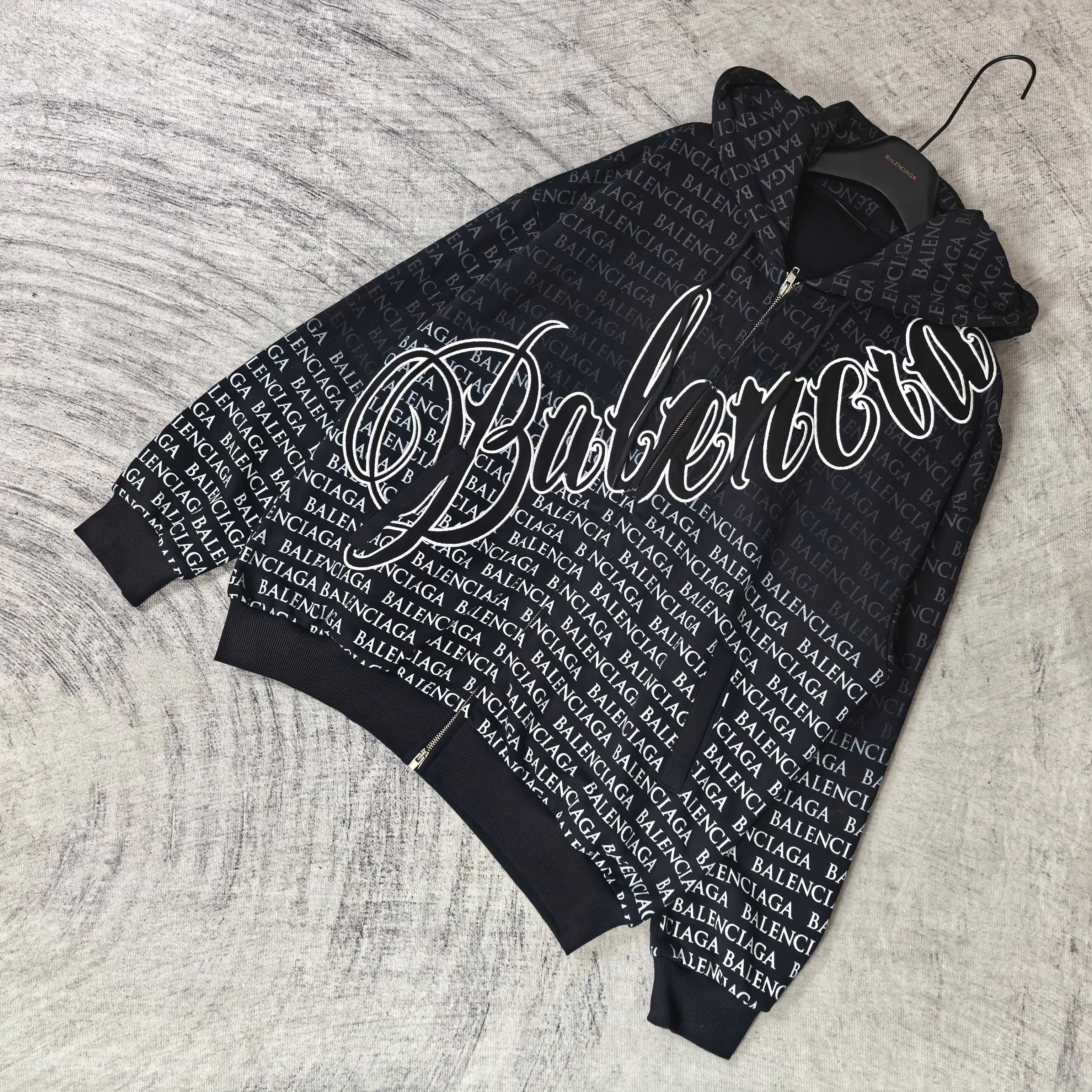 Folded dark zip hoodie set, showing Balenciaga text print and large white graphic detail.