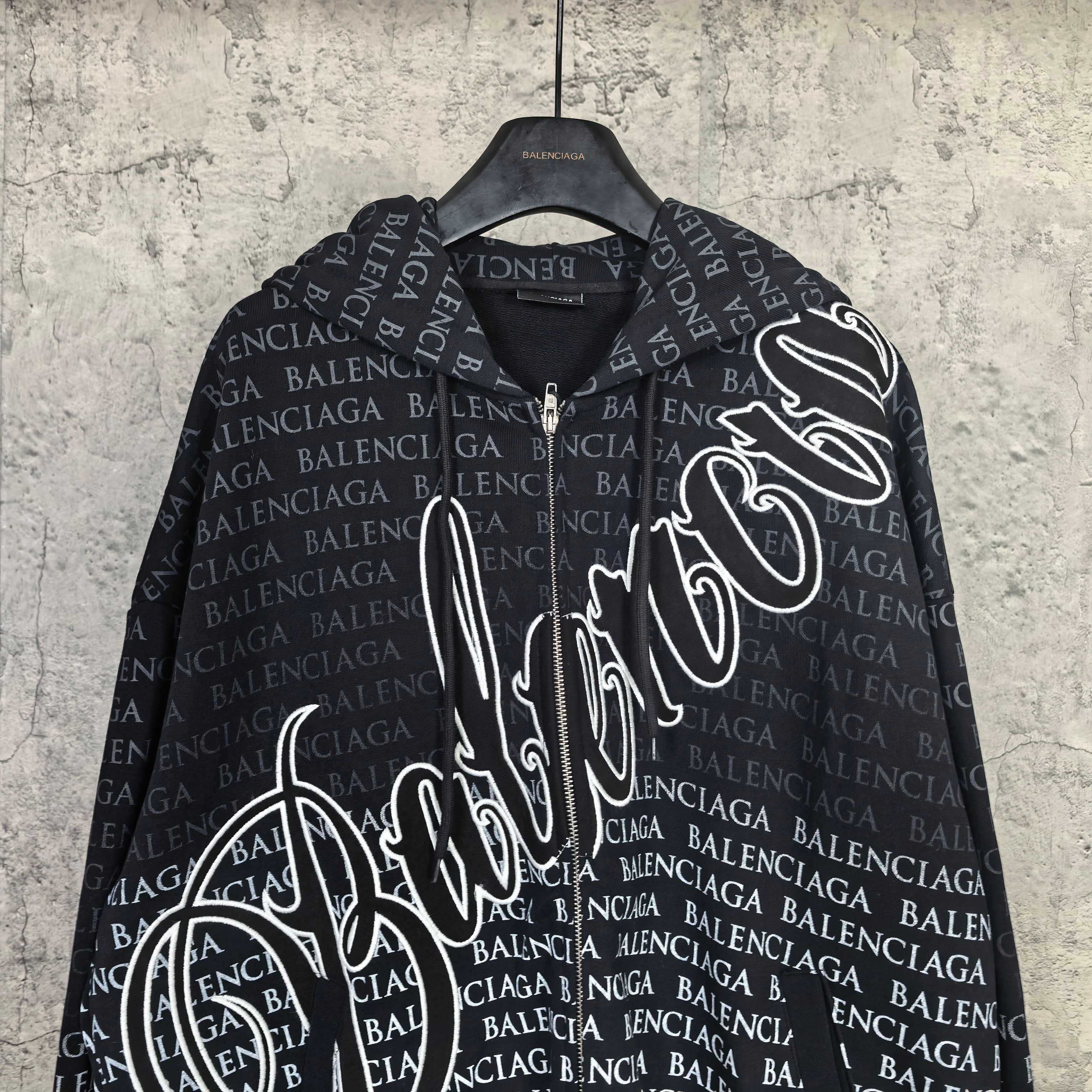 Dark long-sleeve zip hoodie close-up with Balenciaga text print and large front graphic.