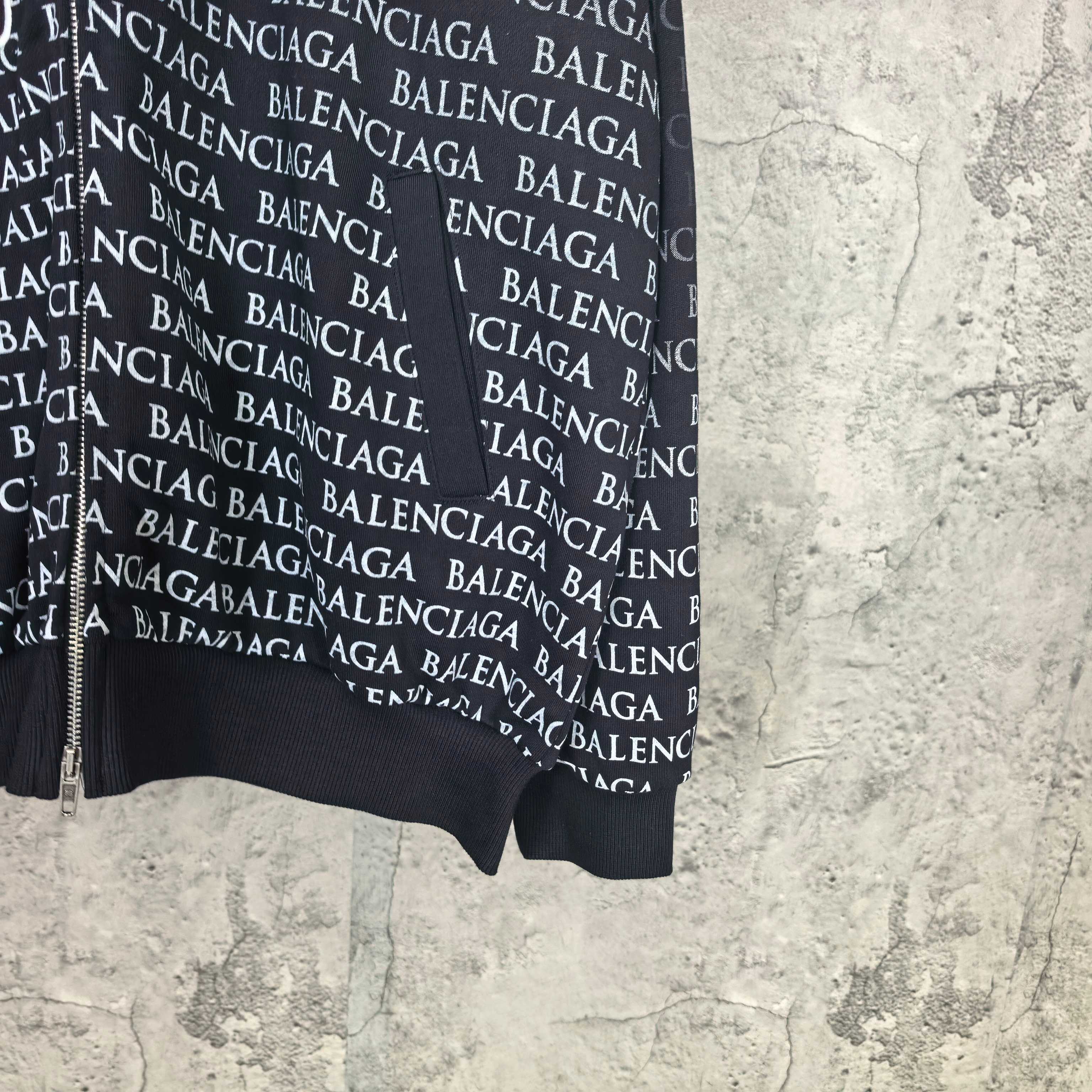 Balenciaga zip-up hoodie, black hem view with repeating BALENCIAGA text and white logo