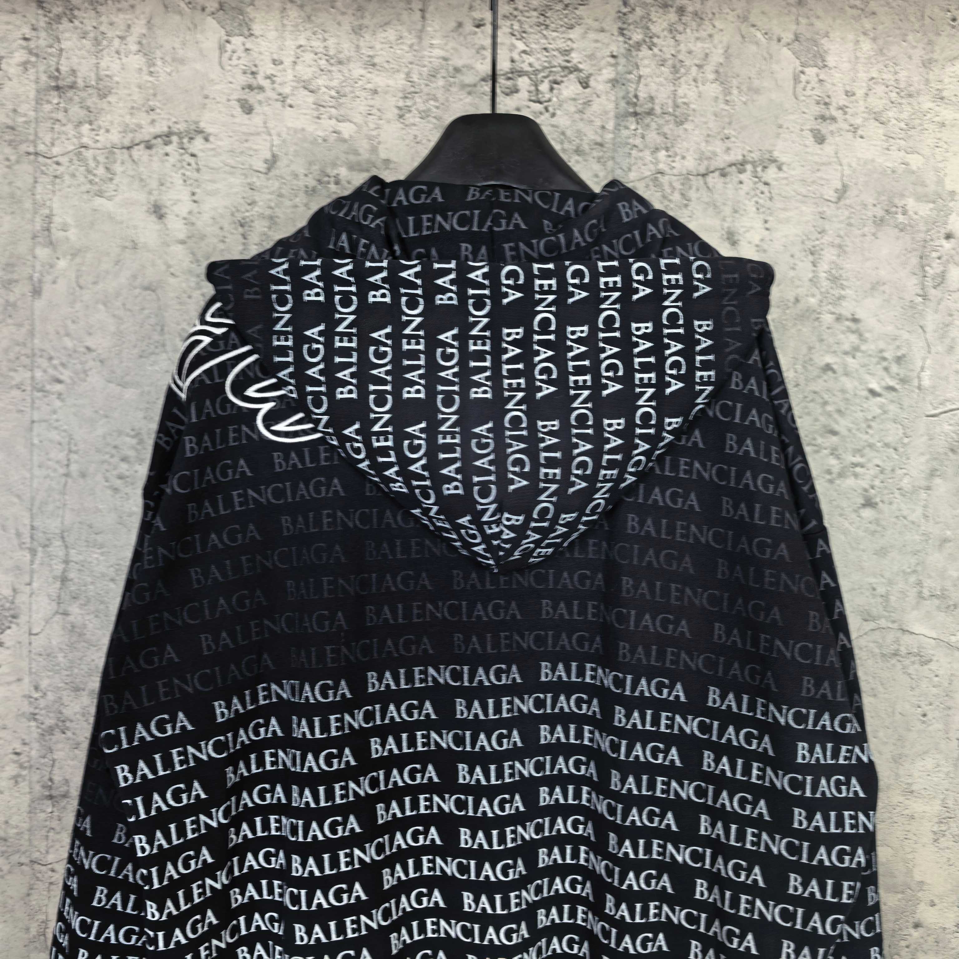 Back of dark long-sleeve zip hoodie with repeating Balenciaga text pattern.