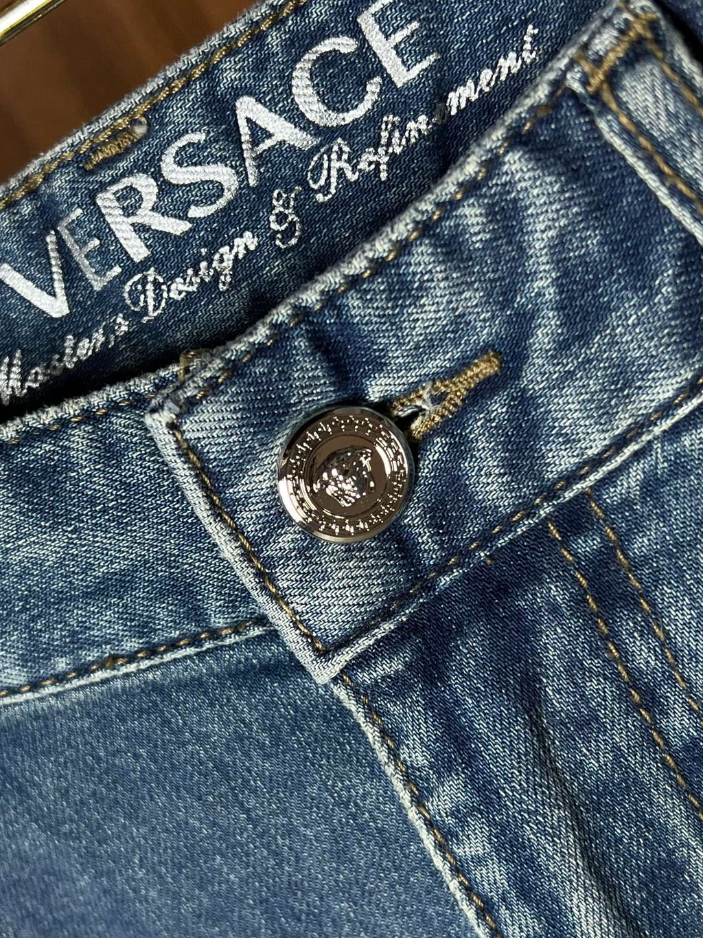 Versace denim jeans close-up of branded waistband label and metal button