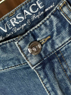Versace denim jeans close-up of branded waistband label and metal button