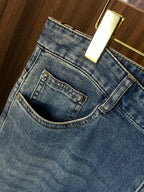 Light blue denim jeans close-up of waist band, curved yoke seam, and pocket openings