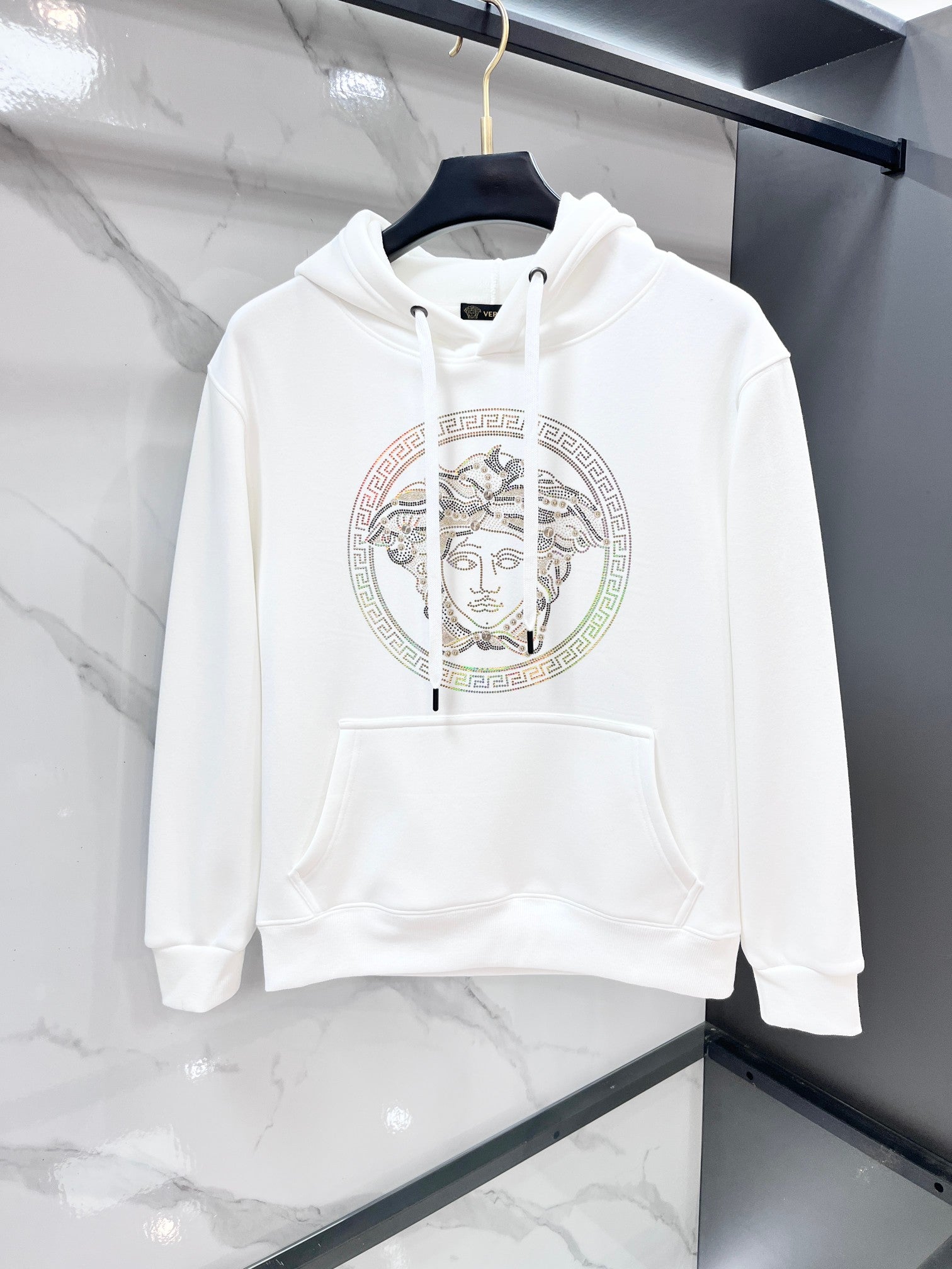 White hooded sweatshirt with drawstrings and large circular Medusa rhinestone print