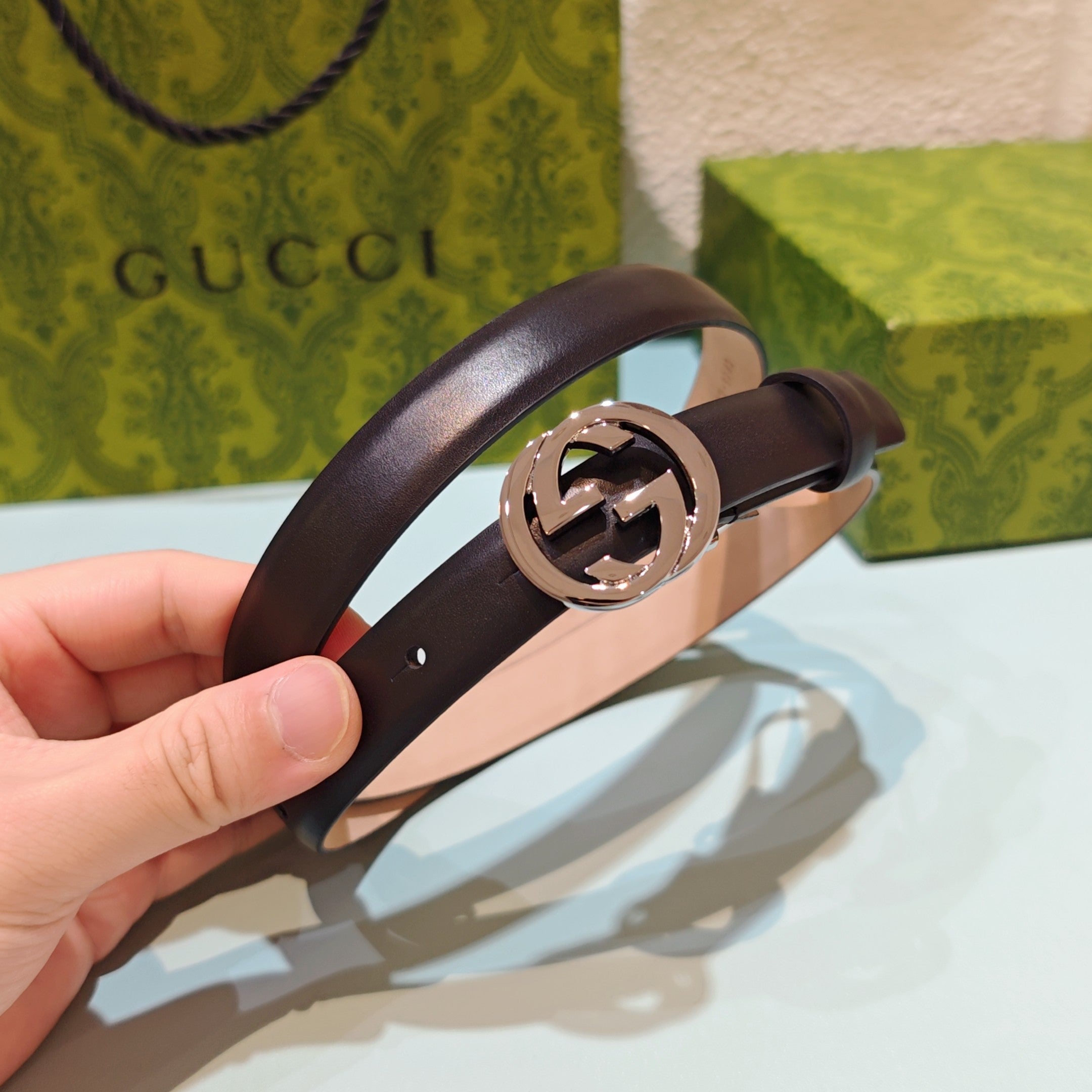 Gucci belt, dark brown leather, featuring a large silver-tone GG buckle close-up.