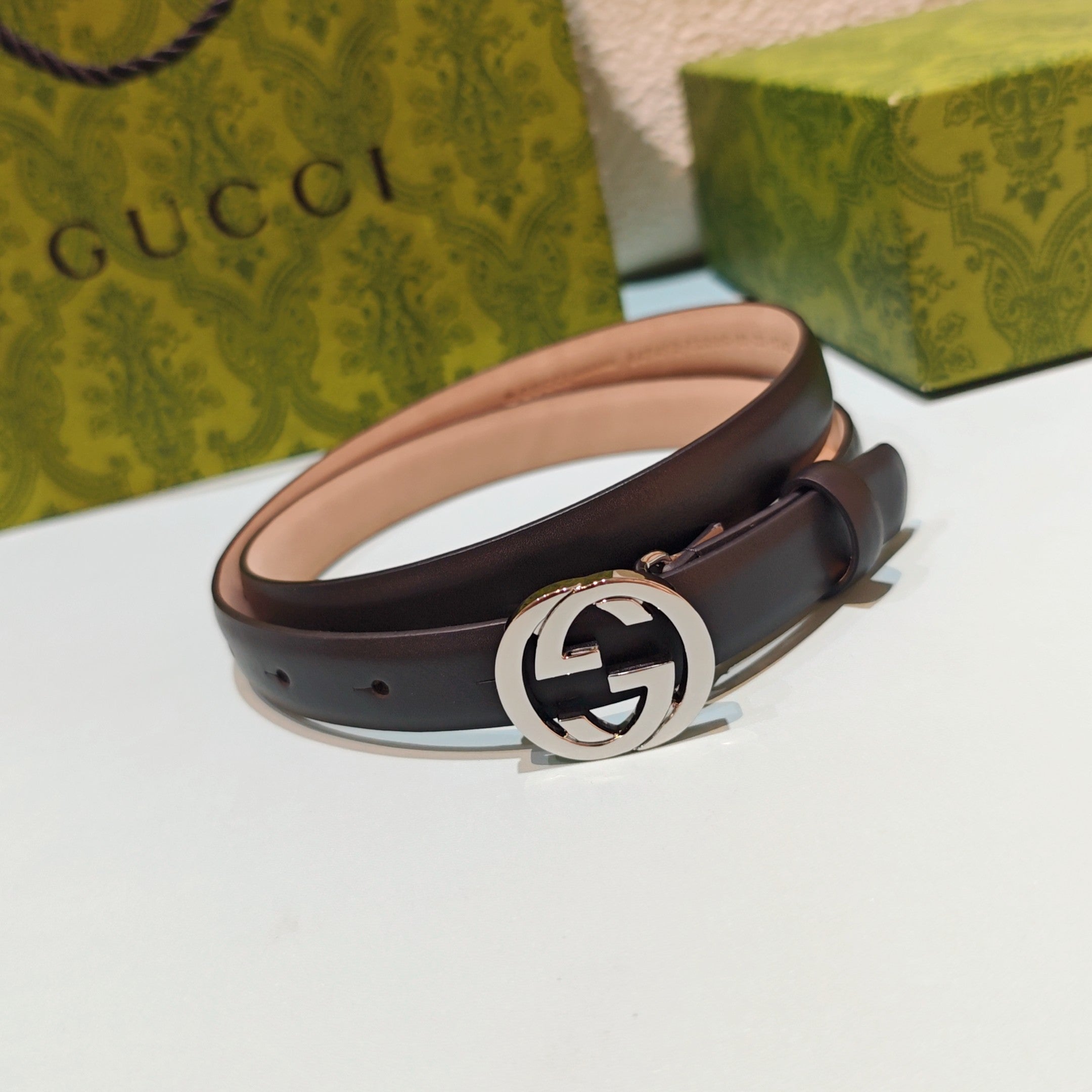 Gucci belt in dark brown leather with polished silver-tone GG buckle, side view.