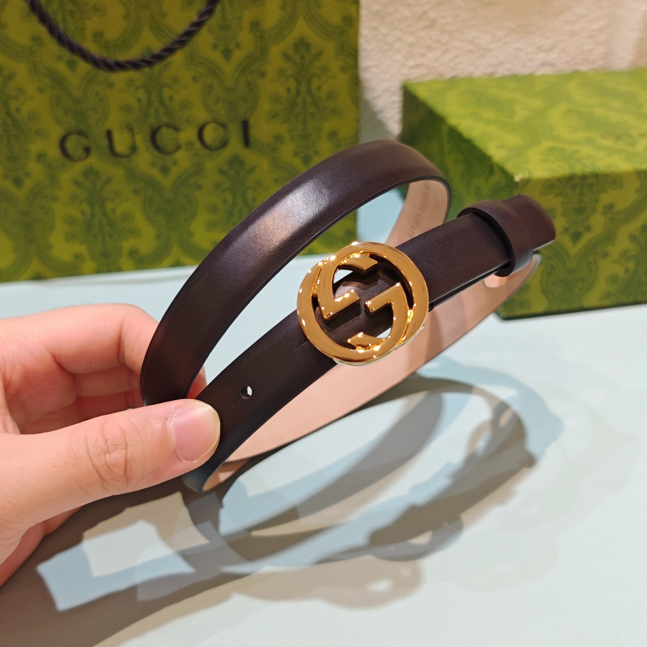 Gucci belt in dark leather with round gold-tone GG buckle, adjustable holes