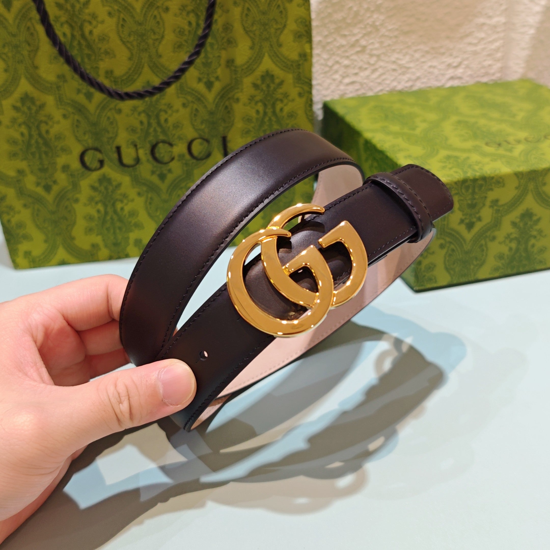 Gucci belt detail: dark leather strap with gold-tone GG buckle and pin holes