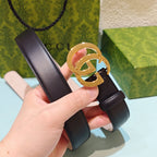 Gucci belt close-up: dark strap, gold GG buckle, held by hand