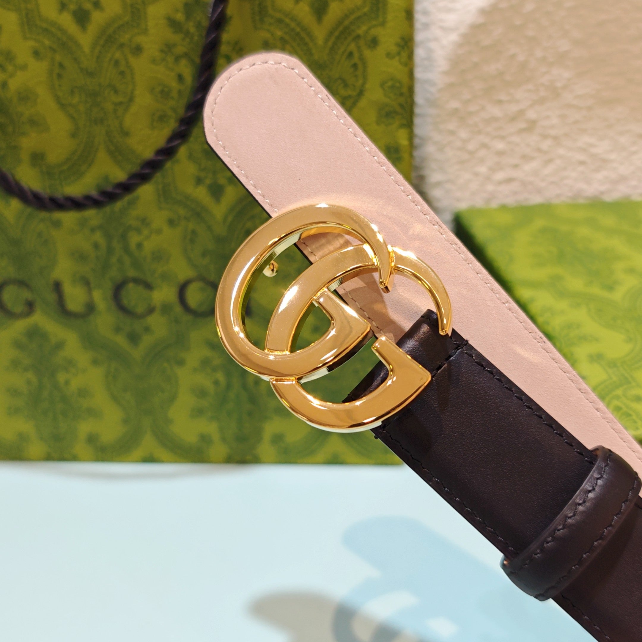 Gucci belt buckle close-up with gold hardware and light pink inner strap