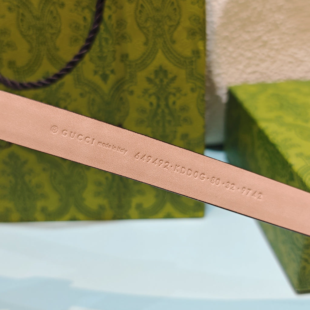 Gucci belt strap in tan leather with stamped Gucci code text along the length.