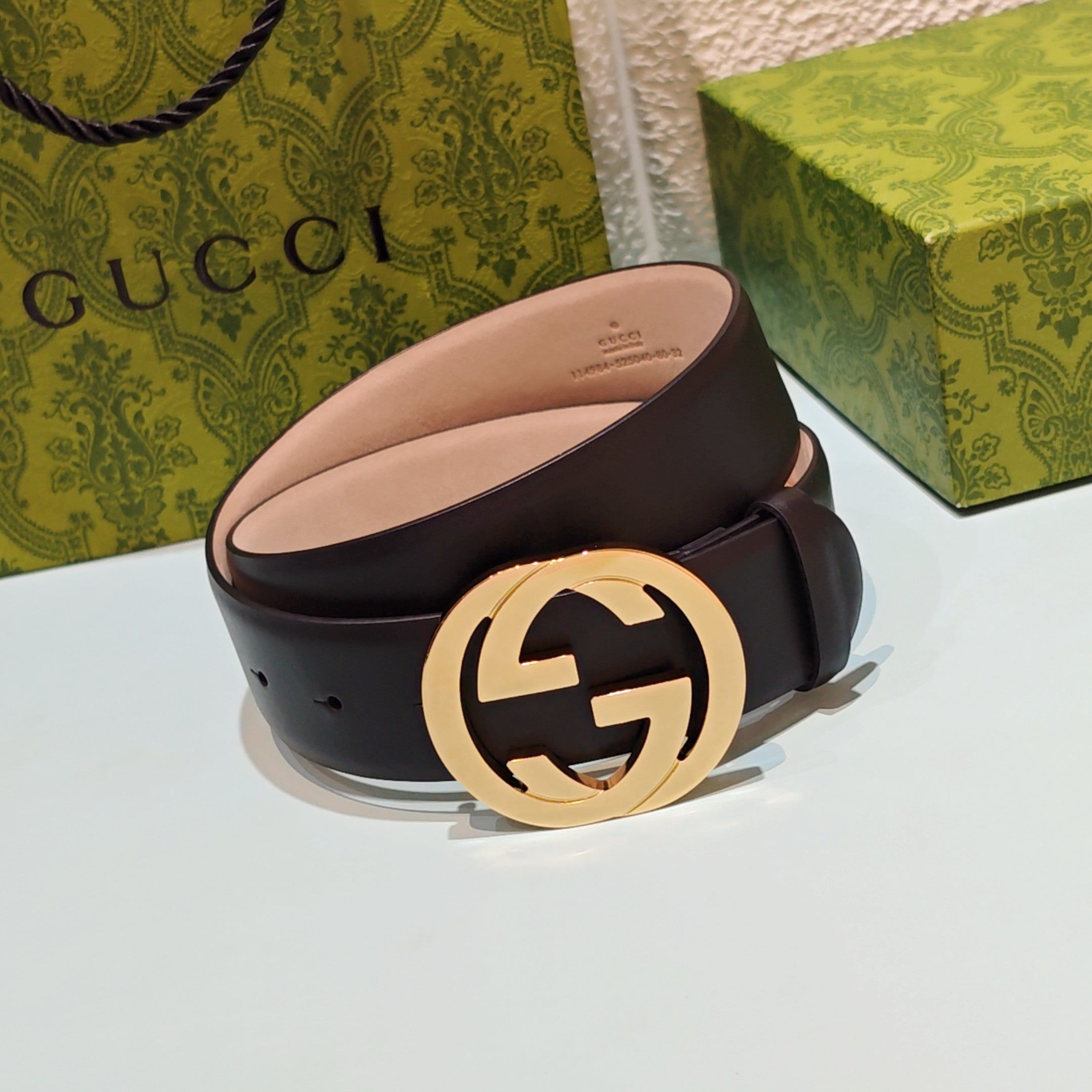 Dark leather belt with gold-tone GG logo buckle, belt interior side visible
