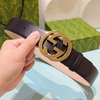 Gucci belt with dark leather strap and gold-tone GG logo buckle, close-up in hand