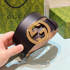 Dark leather belt with gold-tone GG logo buckle, angled view in hand