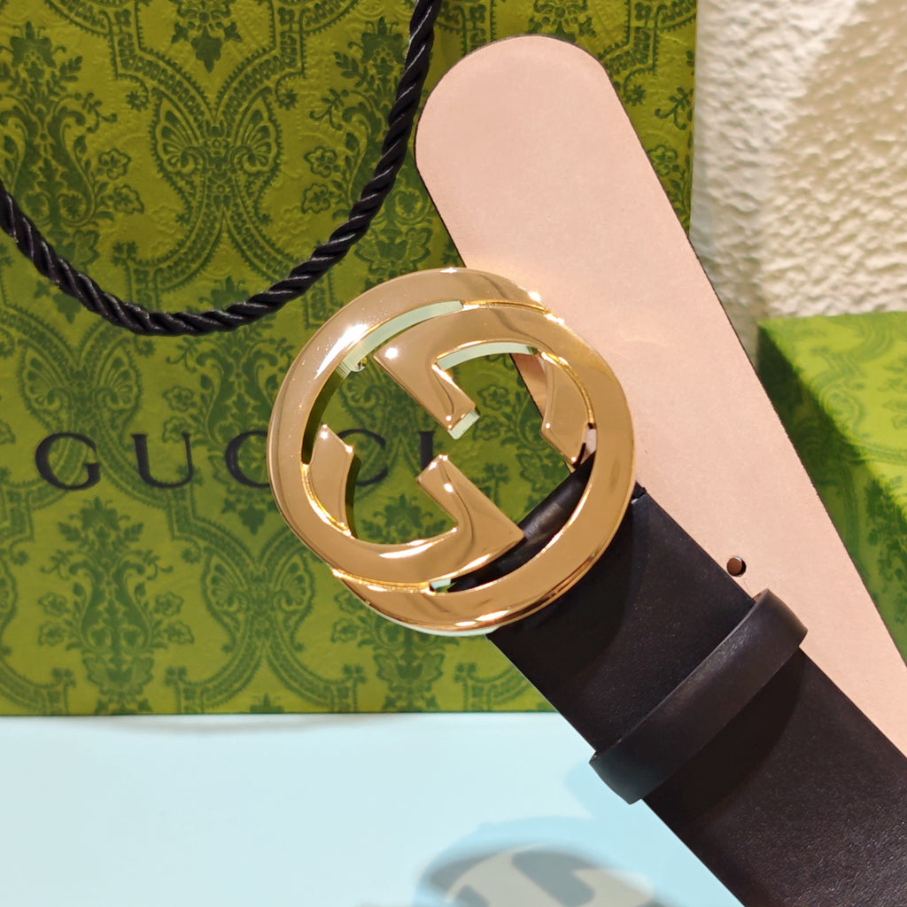 Dark leather belt with oversized gold-tone GG logo buckle, strap end shown