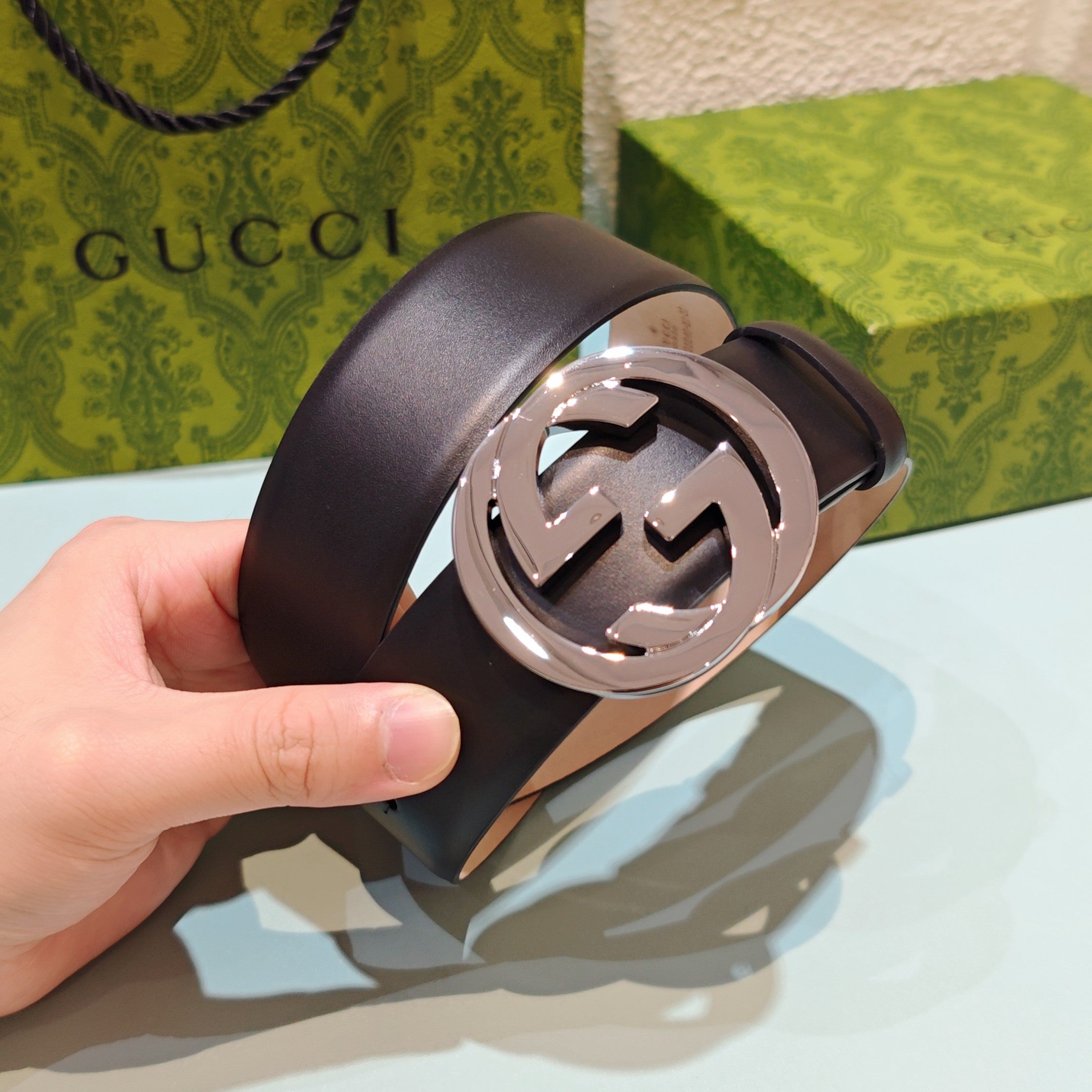 Dark leather belt with close-up oval GG buckle, silver-tone metal hardware
