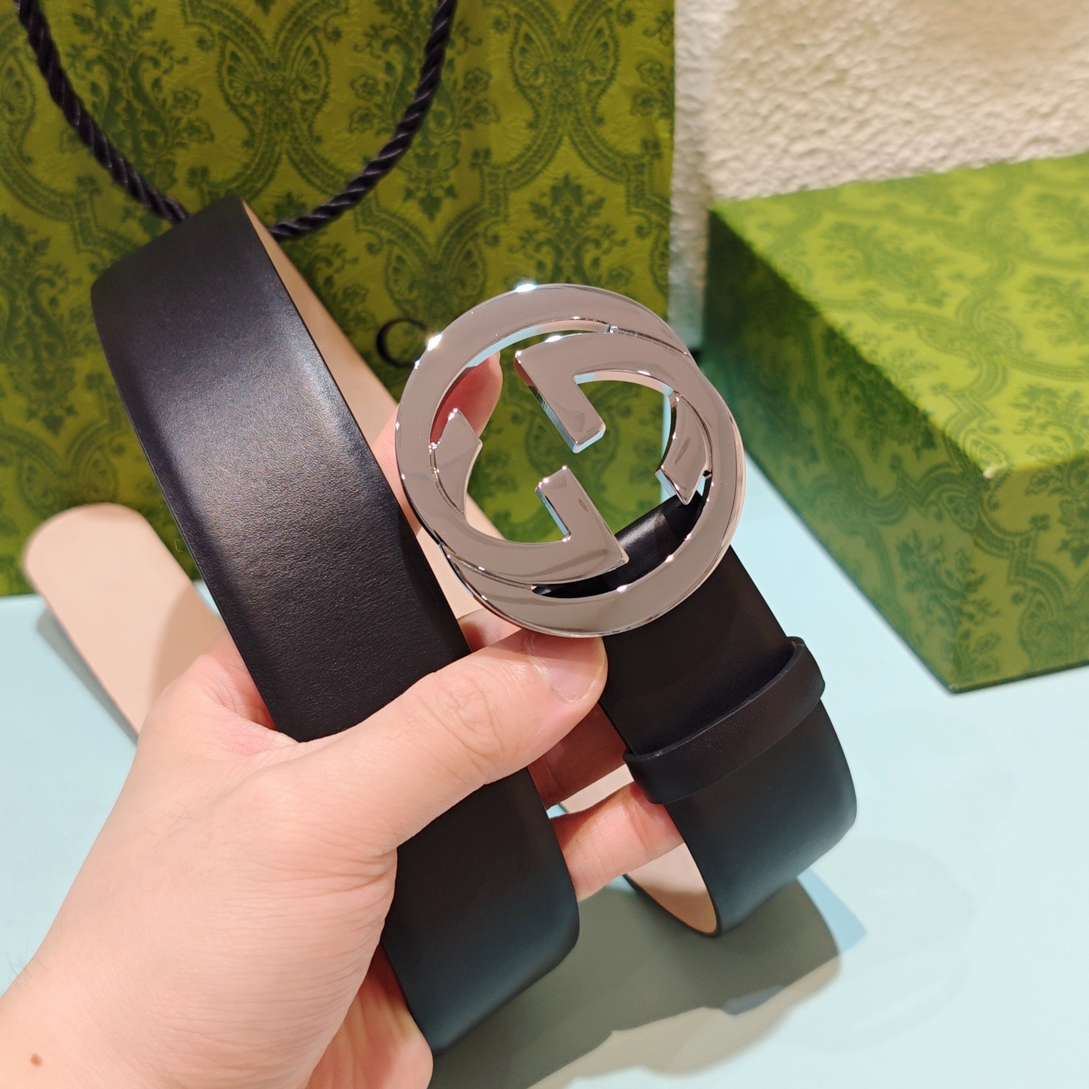 Dark leather belt with GG buckle close-up in silver-tone metal