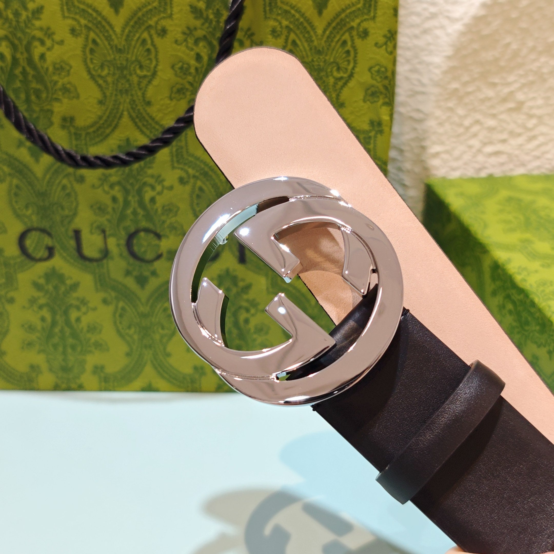 Dark leather belt with polished round GG buckle and light pink inner edge
