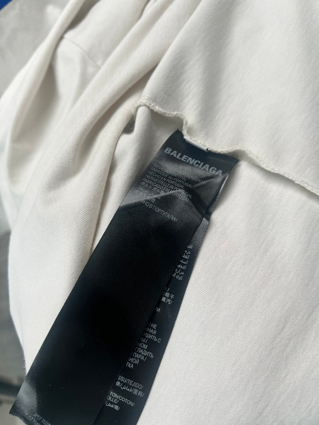 Black fabric care label tag inside white short-sleeve T-shirt