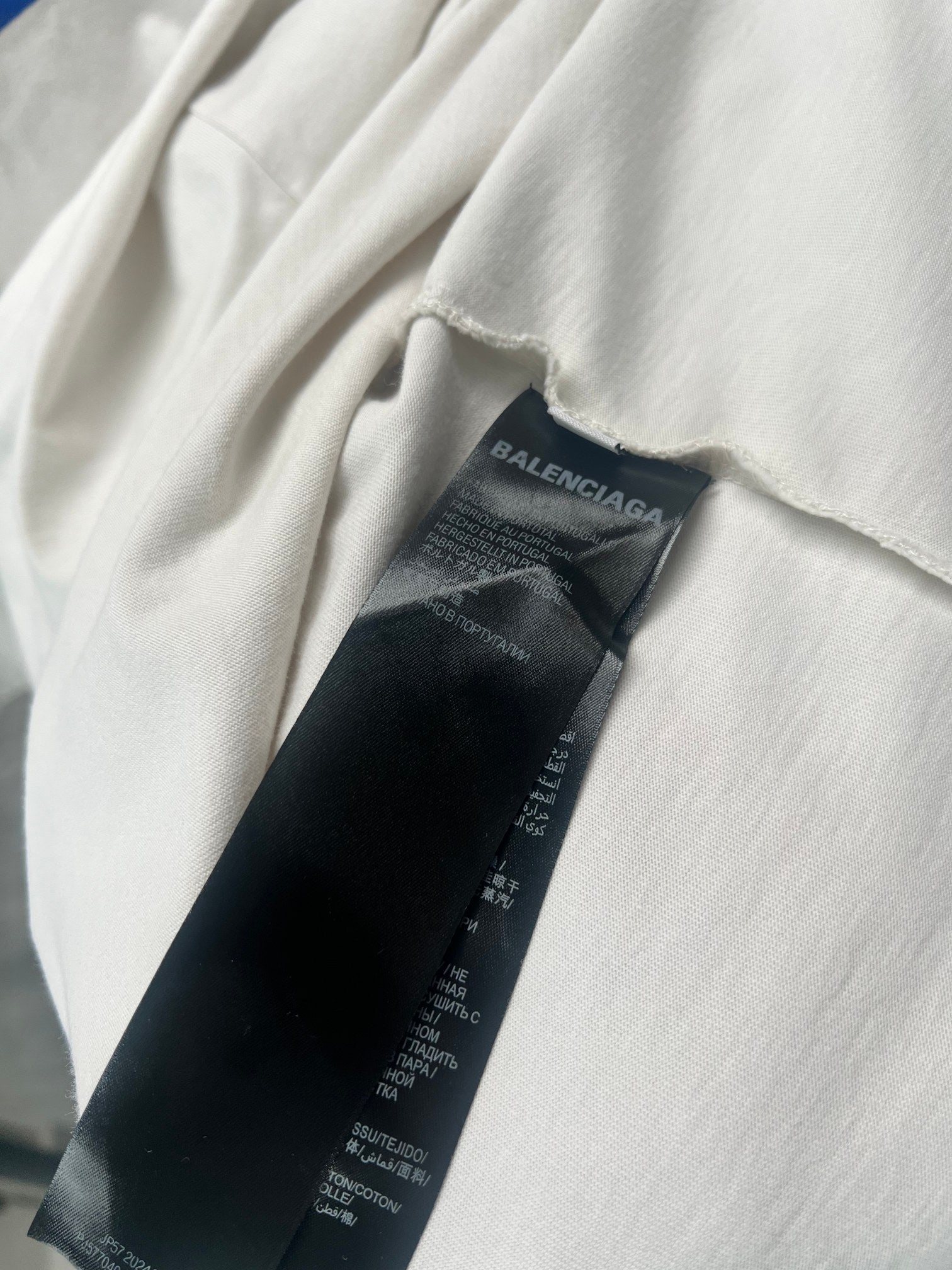 Black fabric care label tag inside white short-sleeve T-shirt