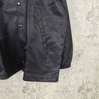 Long black jacket with button front and gathered cuffs, drawstring hem
