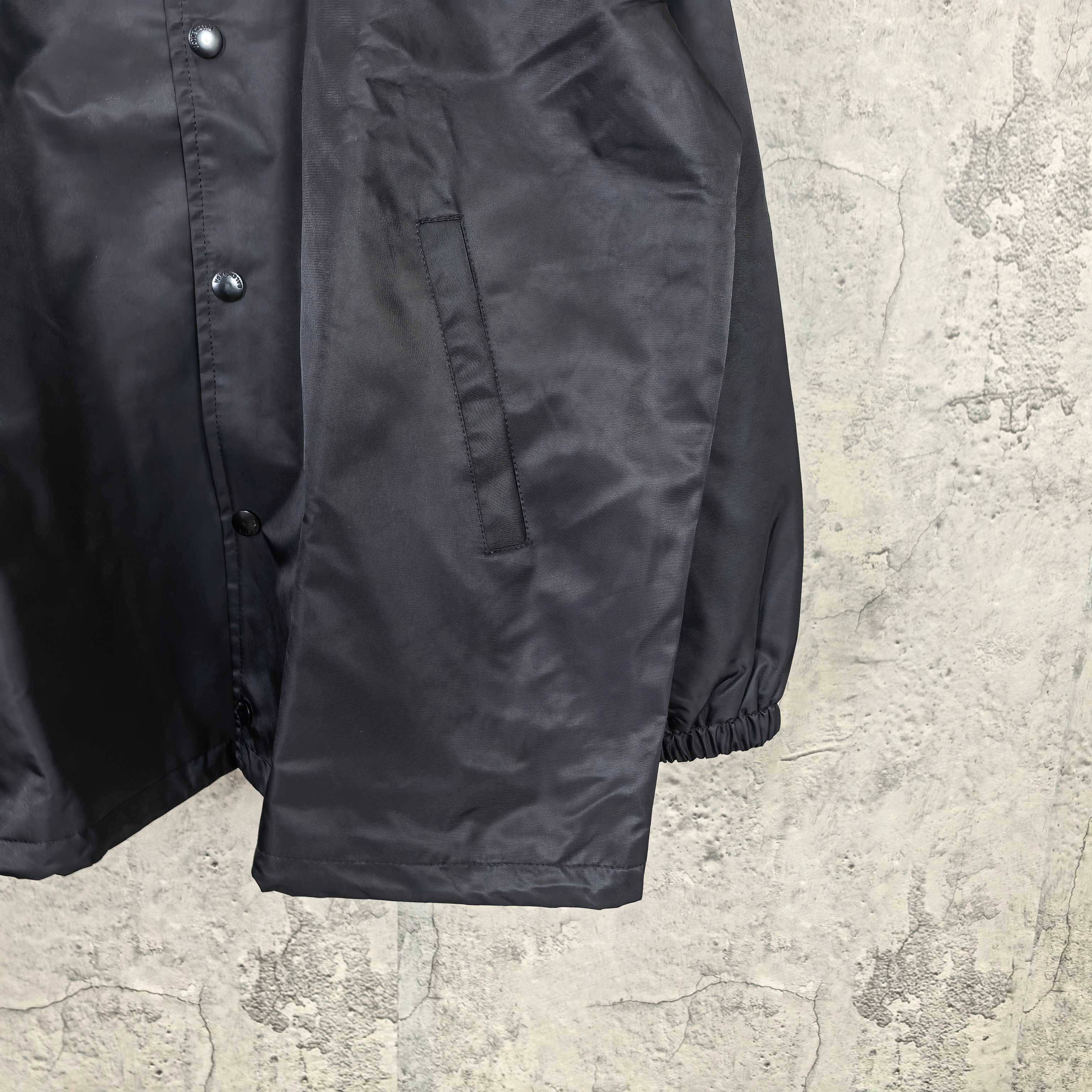 Long black jacket with button front and gathered cuffs, drawstring hem