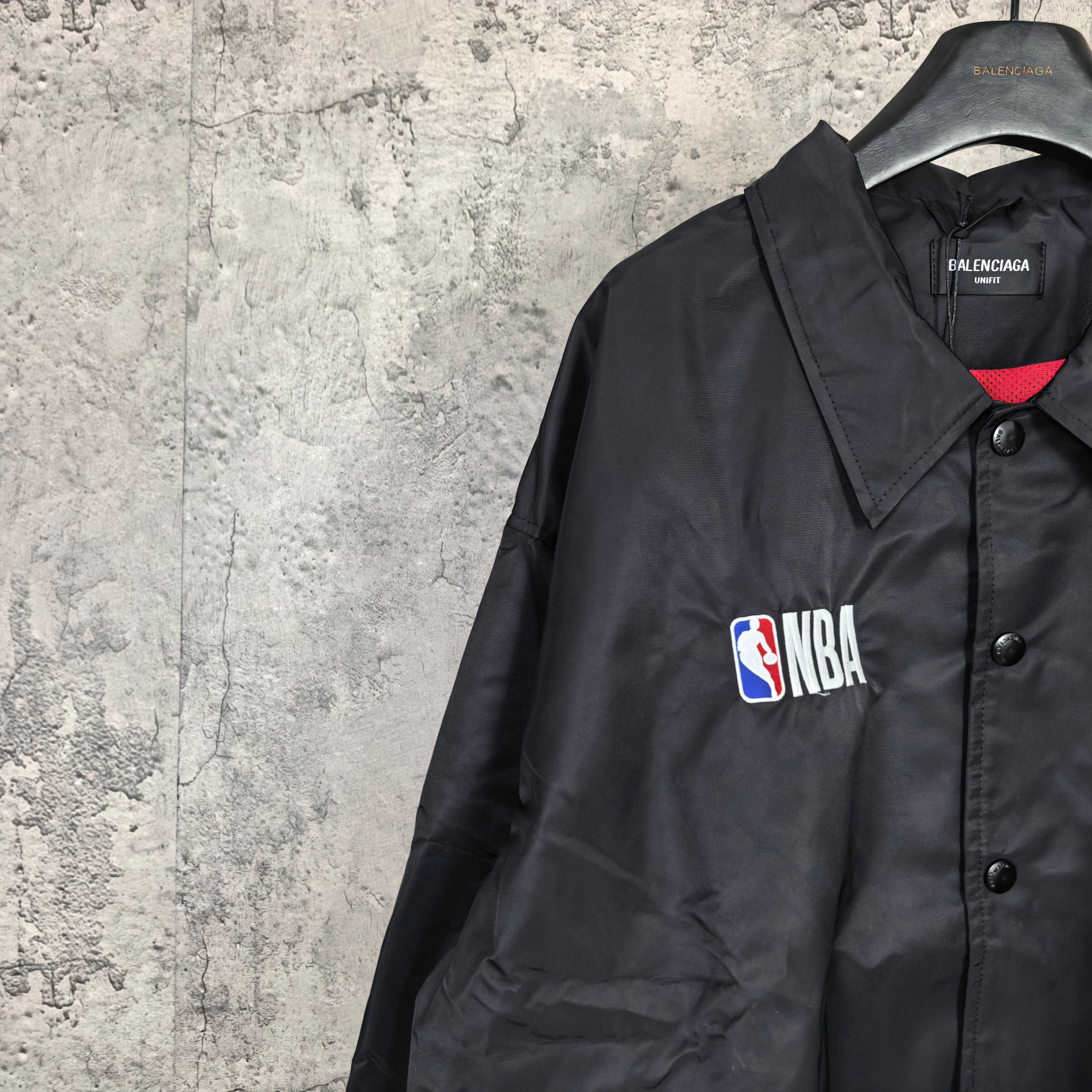 Dark navy jacket shoulder with NBA patch, button placket and red inner collar