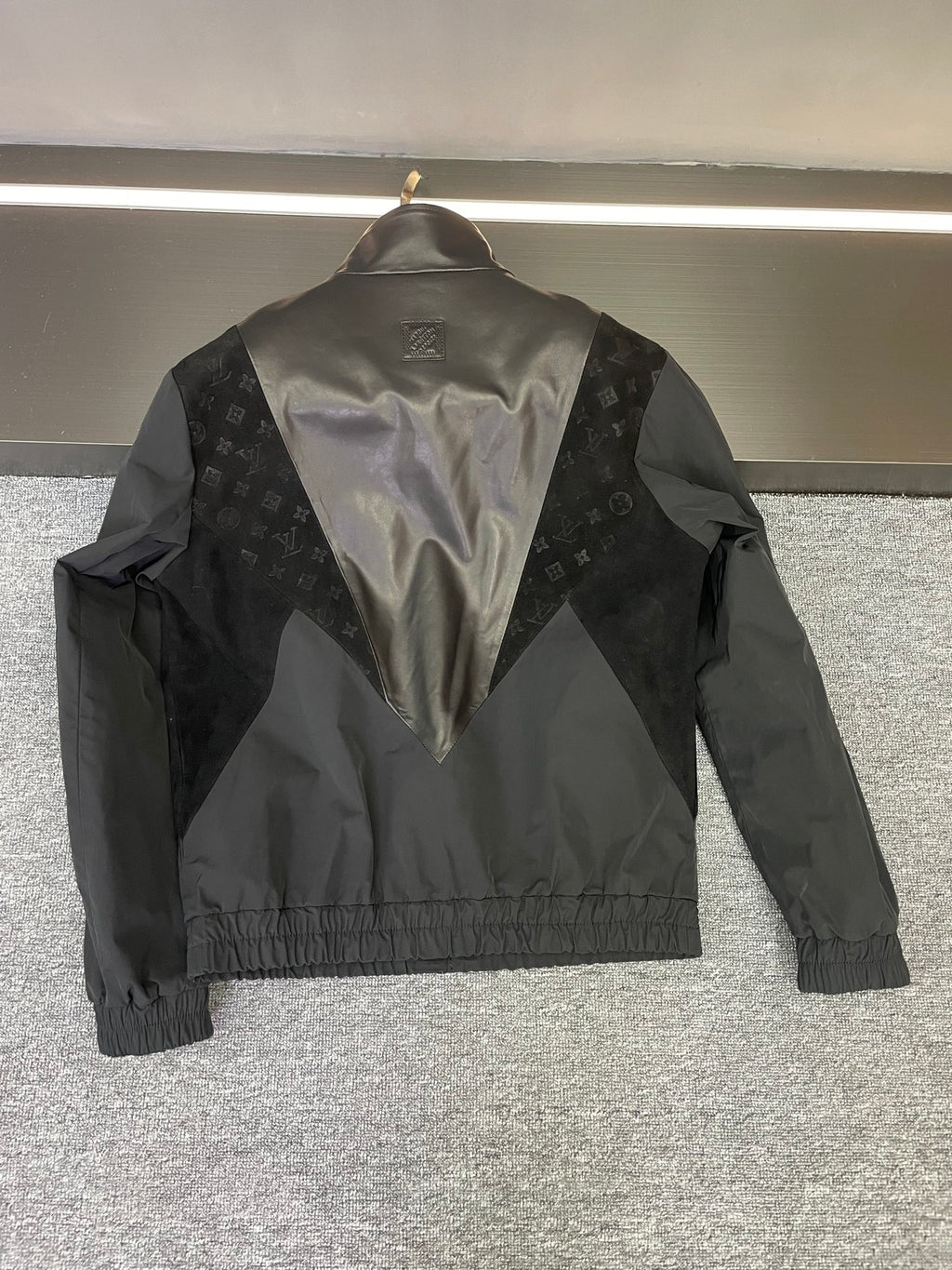 Back of Louis Vuitton jacket with V-shape monogram panel and logo emblem at yoke