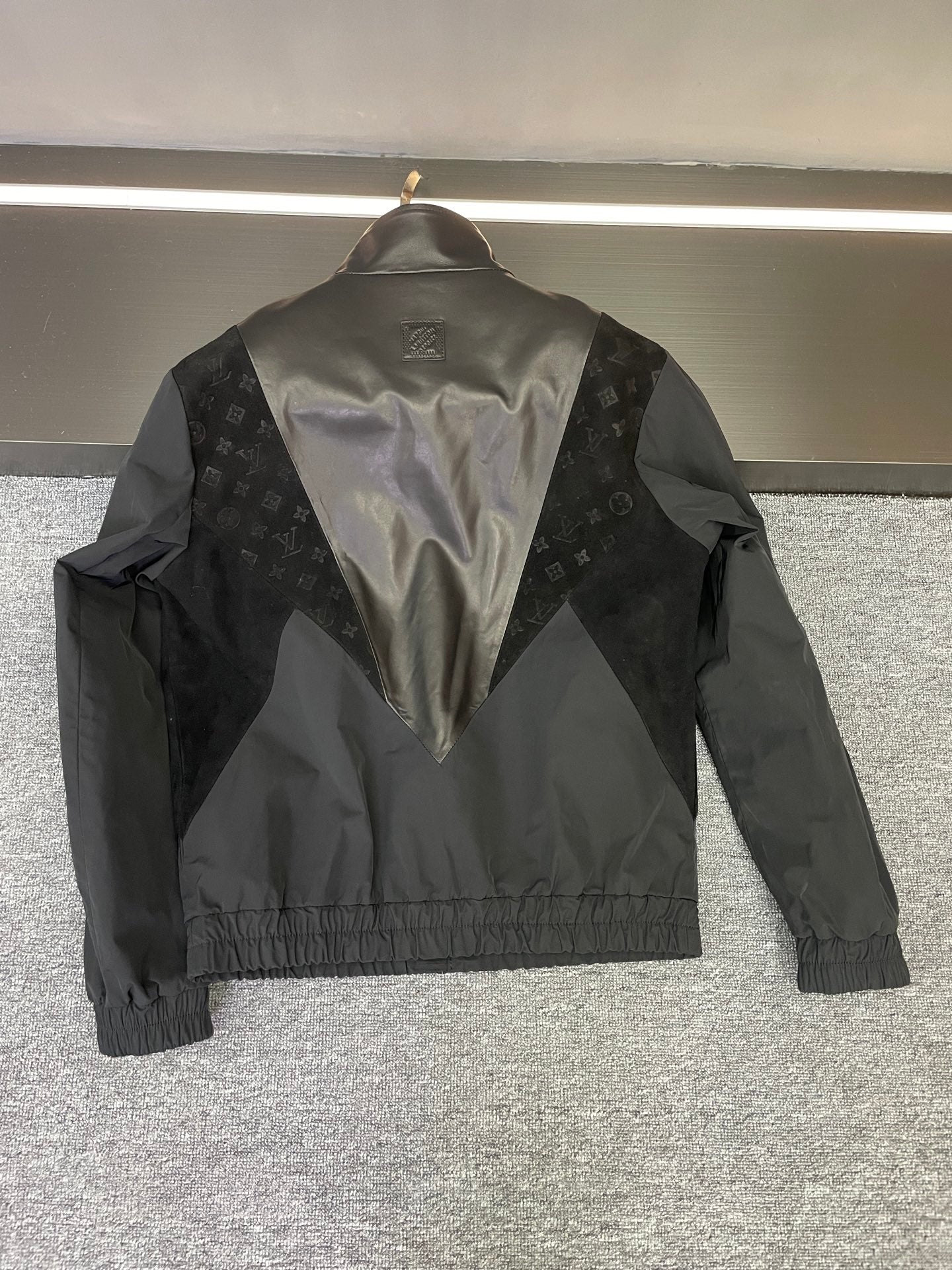 Back of Louis Vuitton jacket with V-shape monogram panel and logo emblem at yoke