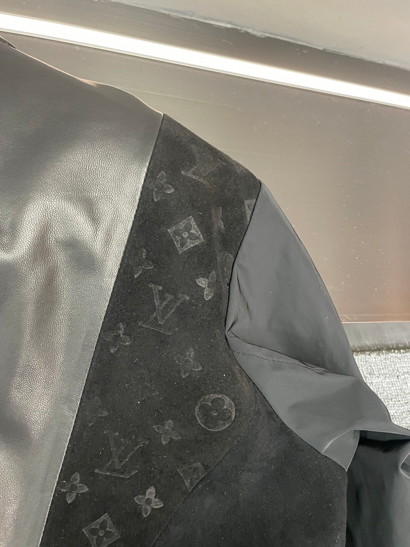 Louis Vuitton jacket interior side, showing black monogram panel and gray lining
