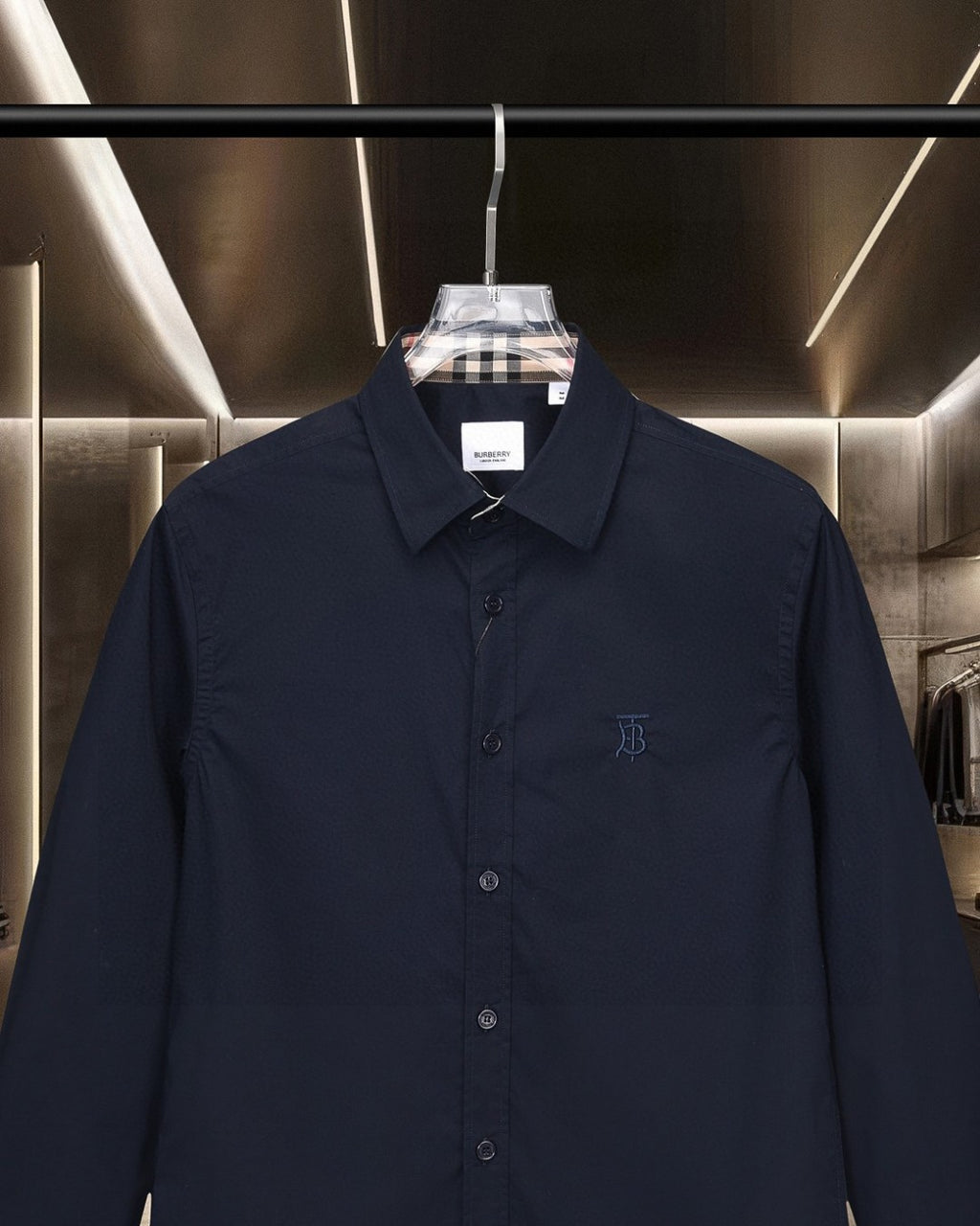 Navy long-sleeve button-up shirt front close-up with TB logo and check inner collar