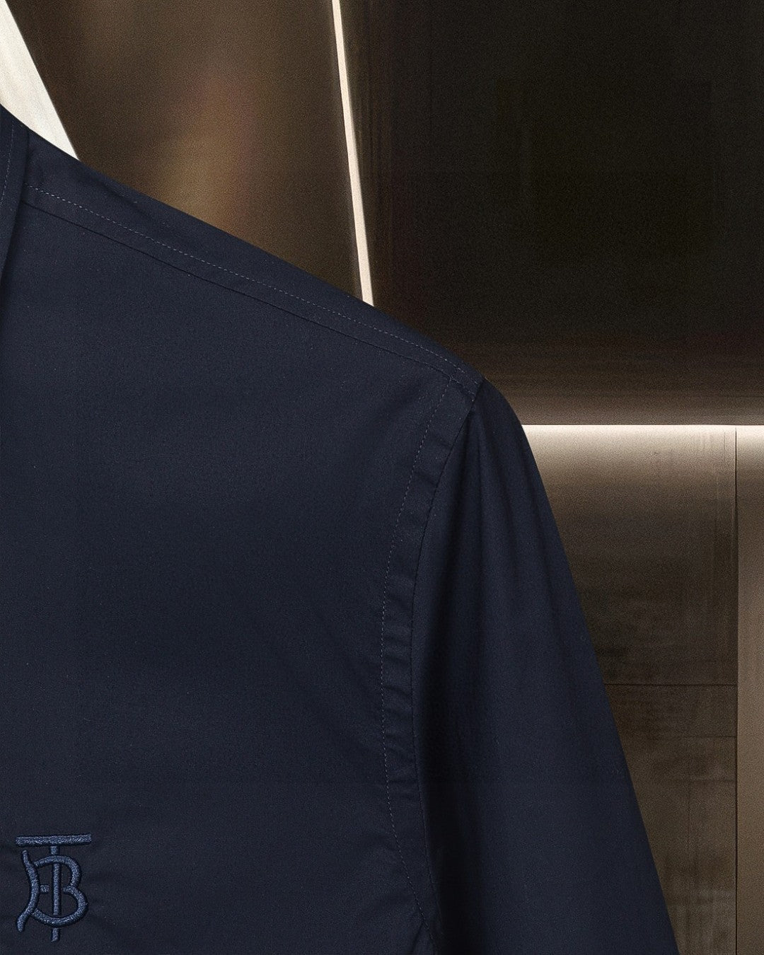 Navy button-up shirt sleeve and side seam detail with TB logo
