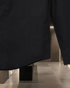 Long coat in dark fabric with straight hem and visible side seam
