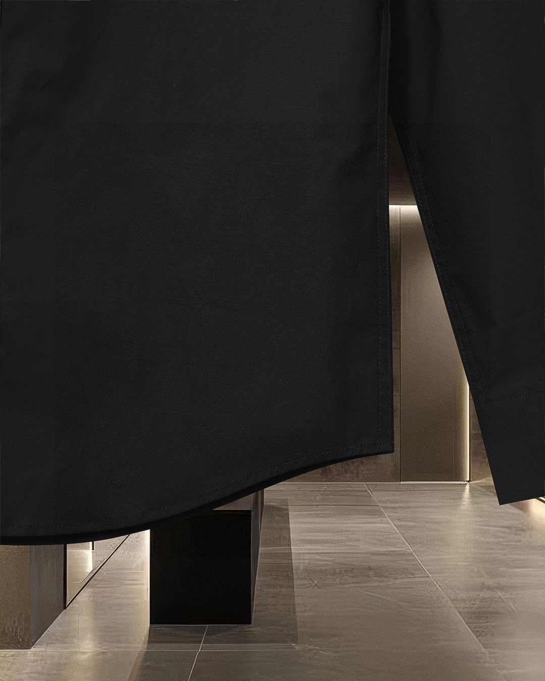 Long coat in dark fabric with straight hem and visible side seam