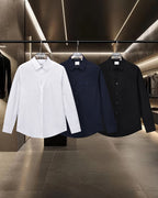 Long-sleeve button-up shirts on rack: white, navy, and black