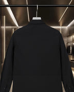 Black long-sleeve button-up shirt, back view on hanger