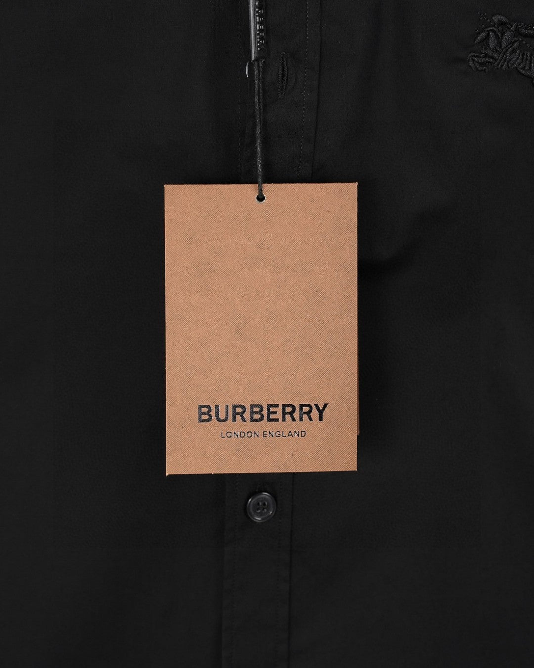 Black shirt chest area with hanging tag and buttoned placket