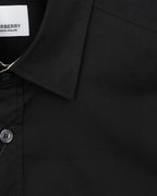 Black shirt sleeve and collar detail with button and stitched seam