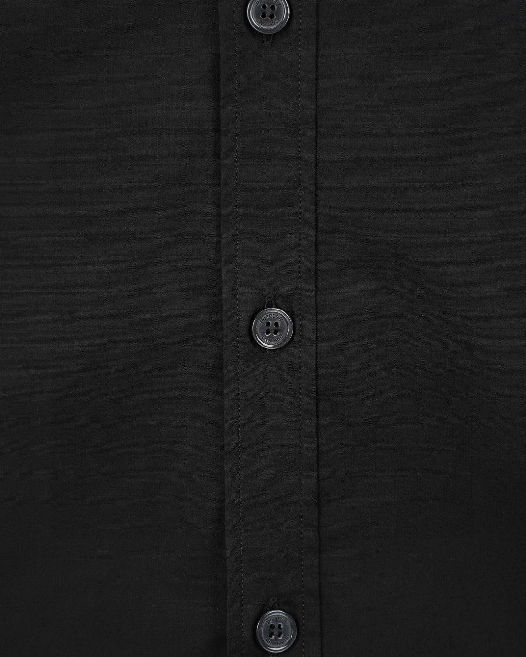 Black shirt front with three visible buttons and vertical stitched placket