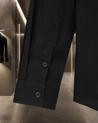 Dark long-sleeve shirt with buttoned front and two visible buttons