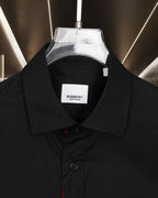 Burberry long-sleeve shirt collar close-up with branded tag, dark black