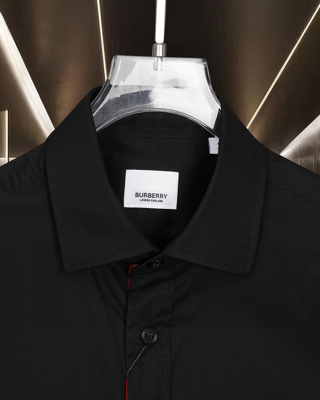 Burberry long-sleeve shirt collar close-up with branded tag, dark black