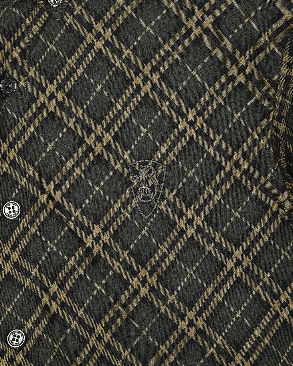 Plaid button-up shirt detail, dark green and yellow grid, crest embroidery near chest